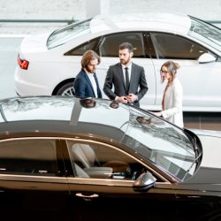 Business couple chosing a new car standing with salesperson in the car showroom. View from above
